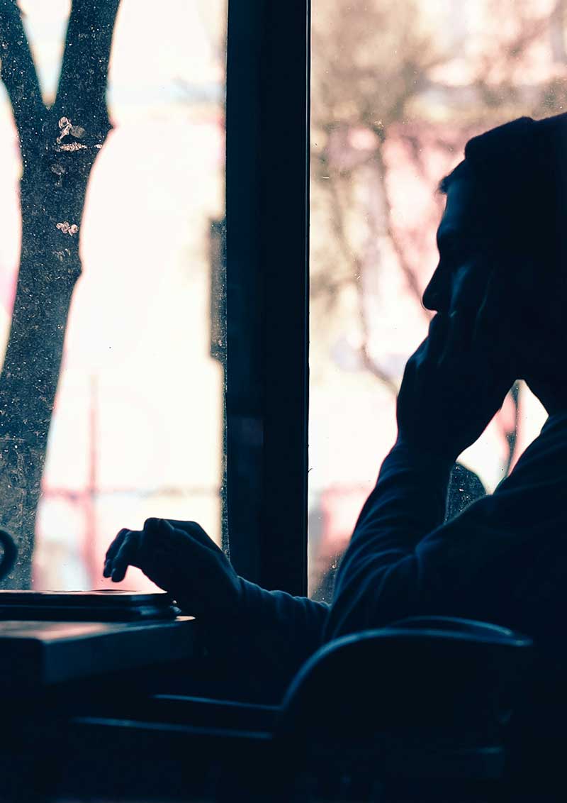 stress-layout Silhouette einer Person, die im Gegenlicht vor einem Laptop sitzt