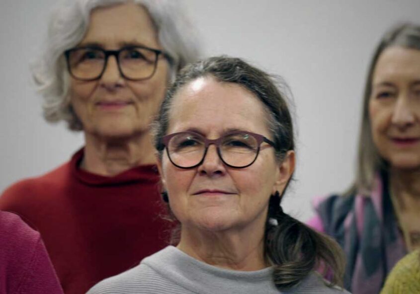 Eine Gruppe älterer Frauen steht nebeneinander und blickt in die Kamera.