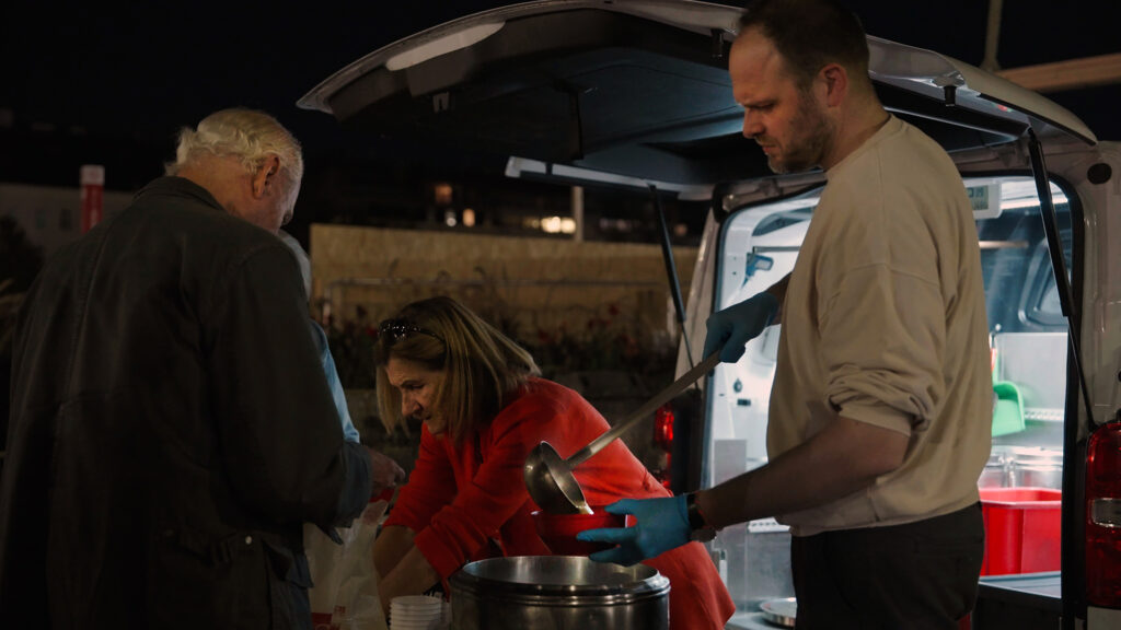 Caritas Canisibus volunteers serving soup from the back of a van at night