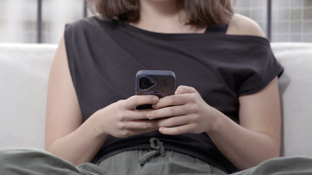 Young woman on a couch typing on her smartphone